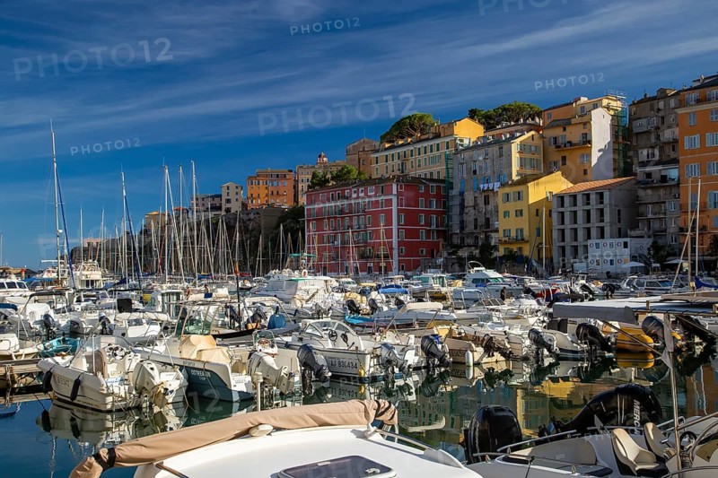 Boats at a lively marina in Corsica, surrounded by colourful buildings under a clear blue sky, Bastia, Corsica, France, Europe