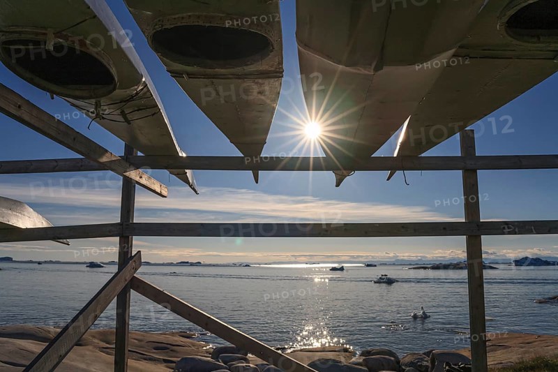 Traditional kayaks on wooden frame in front of icebergs, sun star, summer, Inuit, Ilulissat, Ilulissat Icefjord, Disko Bay, West Greenland, Greenland, North America