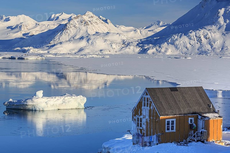 Typical Greenlandic house in front of icebergs, fjord and snowy mountains, sunny, Inuit settlement, winter, Arctic, Kulusuk, East Greenland, Greenland, North America