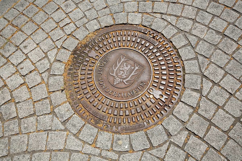Round manhole cover with town coat of arms, paving stones, floor, Sondershausen, Thuringia, Germany, Europe