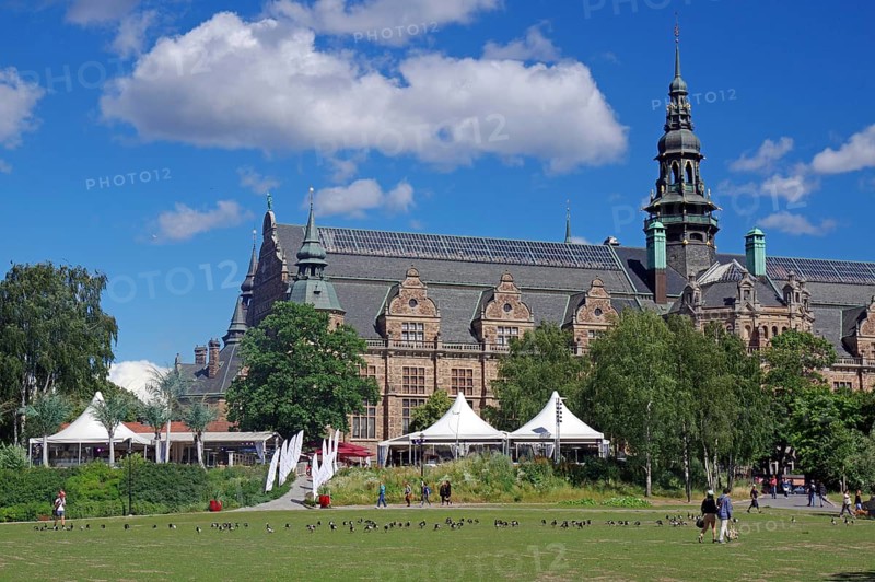 Historic building with striking architecture next to a green space and people under a clear sky, Vasa Museum, Stockholm, Sweden, Europe