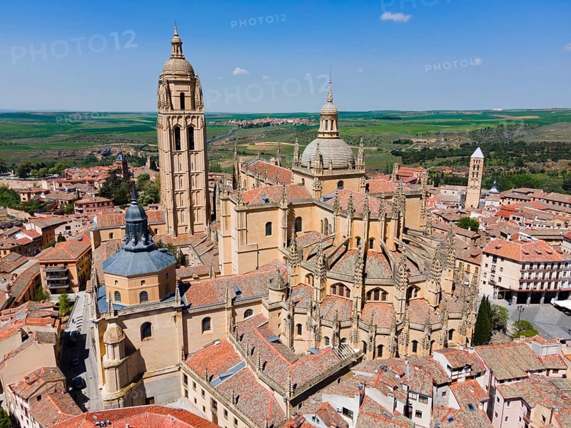 Aerial view of a historic city with a large church and red roofs under a clear blue sky, surrounded by a wide green area, aerial view, Cathedral, Alcazar left, Alcazar, Segovia, Castilla y Leon, Leon, Spain, Europe