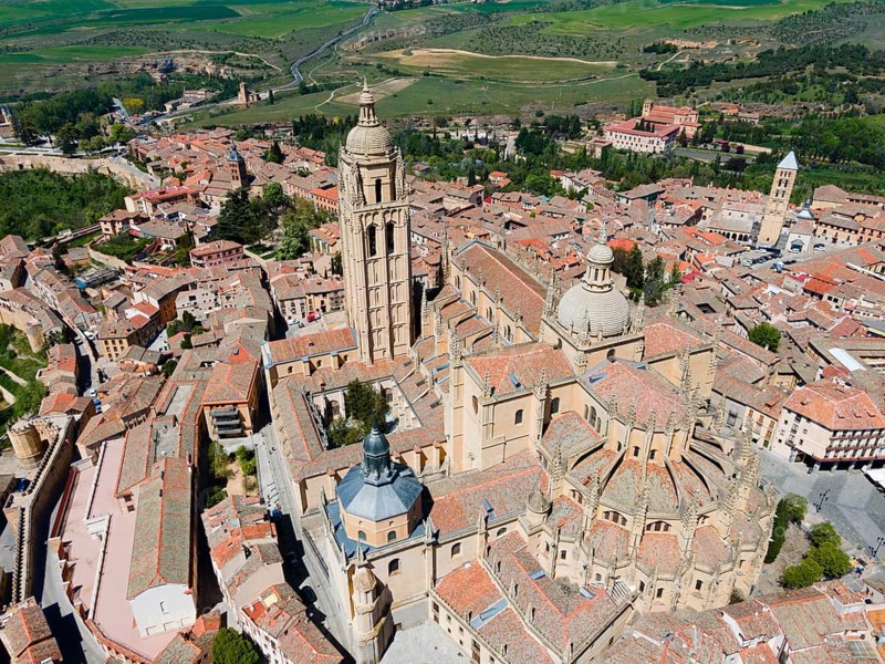 Panoramic view of a medieval city with a prominent church surrounded by green countryside and historic buildings under a clear blue sky, aerial view, Cathedral, Segovia, Castilla y Leon, Leon, Spain, Europe
