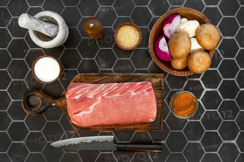Overhead view of raw pork fillet, fresh champignons and spice ready for cooking