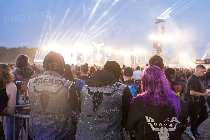 Festival visitors with Wacken jackets look at the two main stages Faster and Harder at dusk at the Wacken Open Air in Wacken. The traditional metal festival takes place from 31 July to 3 August 2024