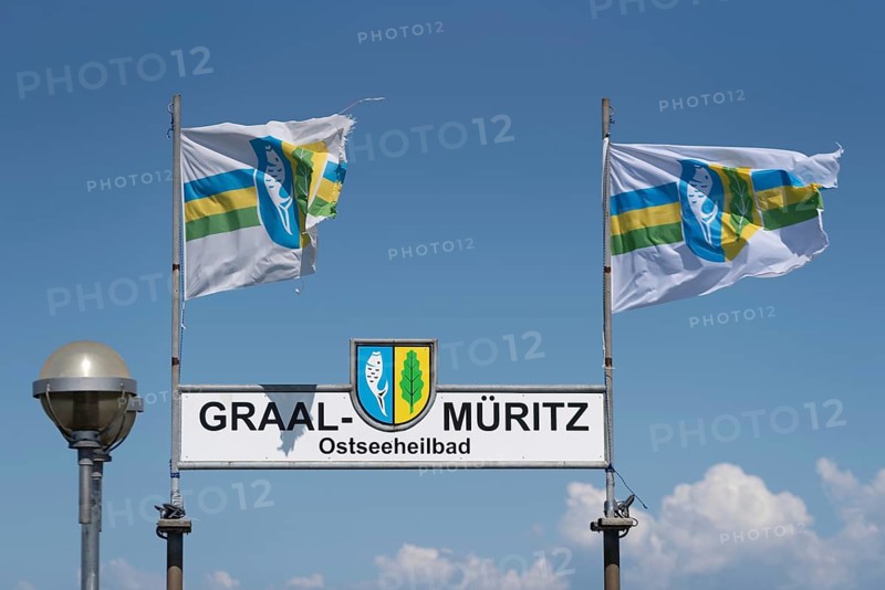 Two flags and a sign with the inscription Graal-Müritz Ostseeheilbad under a clear blue sky with few clouds, Graal-Müritz, Mecklenburg-Vorpommern, Germany, Europe