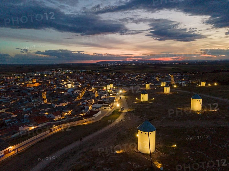 Illuminated windmills and a village in the light of dusk. The sky shows bright colours of the sunset and the atmosphere is calm. Aerial view, windmills, Campo de Criptana, province of Ciudad Real, Castilla-La Mancha, Route of Don Quixote, Spain, Europe