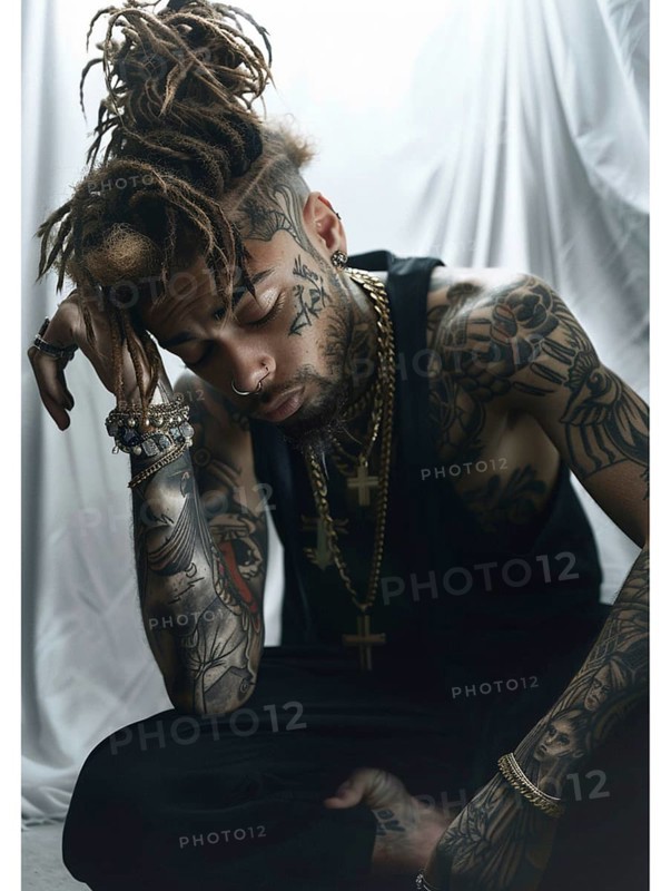 A tattooed man with dreadlocks sits pensively, adorned with multiple pieces of jewelry and wearing a black shirt, AI generated