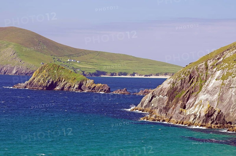Dramatic coastline with high green cliffs and blue ocean waters under clear skies, Slea Head Drive, Dingle, Ireland, Europe