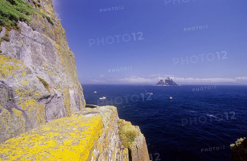 Rocky cliffs overlooking the sea and a distant island, view of the Skellig Islands, Ring of Kerry, Ireland, Europe