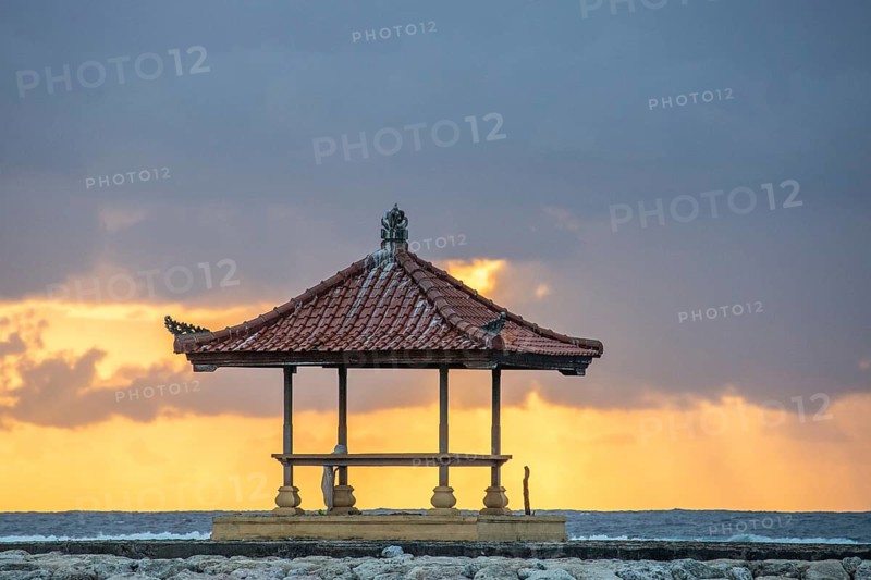 Fantastic sunrise on the beach with small temples and built as breakwaters. View of the sea as far as the horizon. Sanur, Bali, Indonesia, Asia