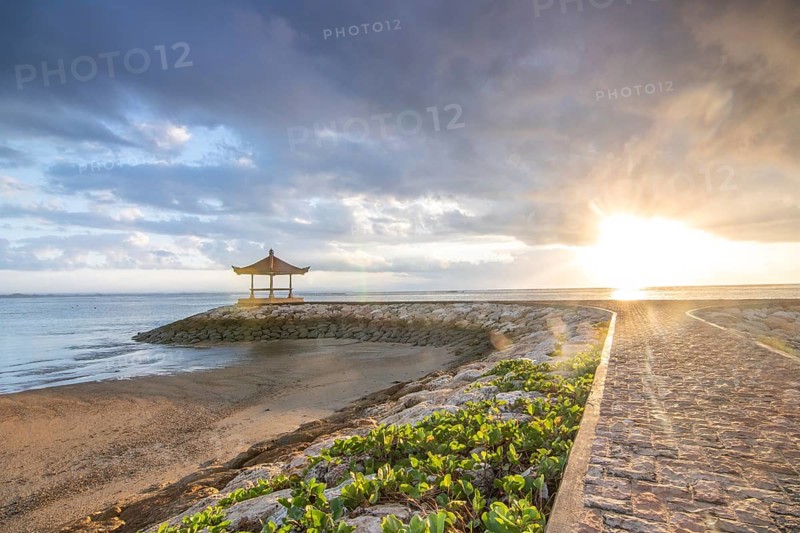 Fantastic sunrise on the beach with small temples and built as breakwaters. View of the sea as far as the horizon. Sanur, Bali, Indonesia, Asia