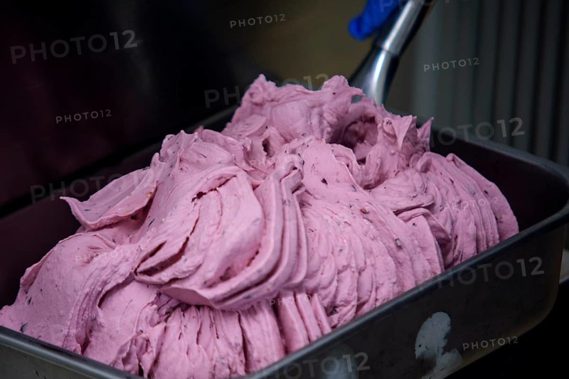 Close up of a professional ice cream machine mixing a delicious pink fruit flavor ice cream, the finished product ready to be served