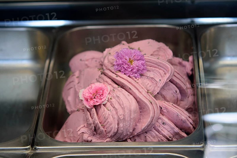 Pink ice cream with flower decorations, neatly arranged in a stainless steel tray