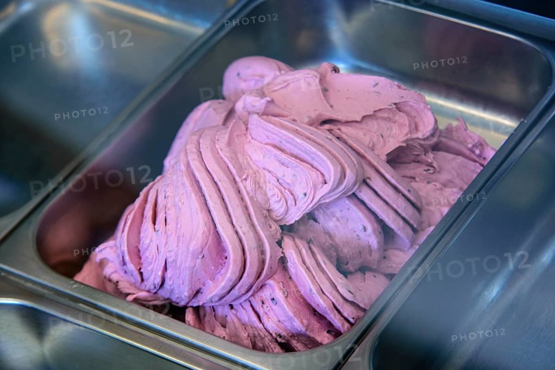 Close-up of pink ice cream being prepared in a stainless steel tray