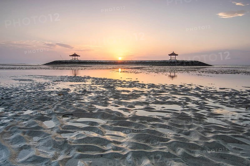 Fantastic sunrise on the beach with small temples. View of the sea as far as the horizon. Sanur, Bali, Indonesia, Asia