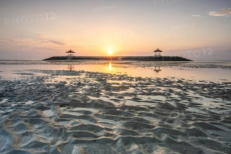 Fantastic sunrise on the beach with small temples. View of the sea as far as the horizon. Sanur, Bali, Indonesia, Asia