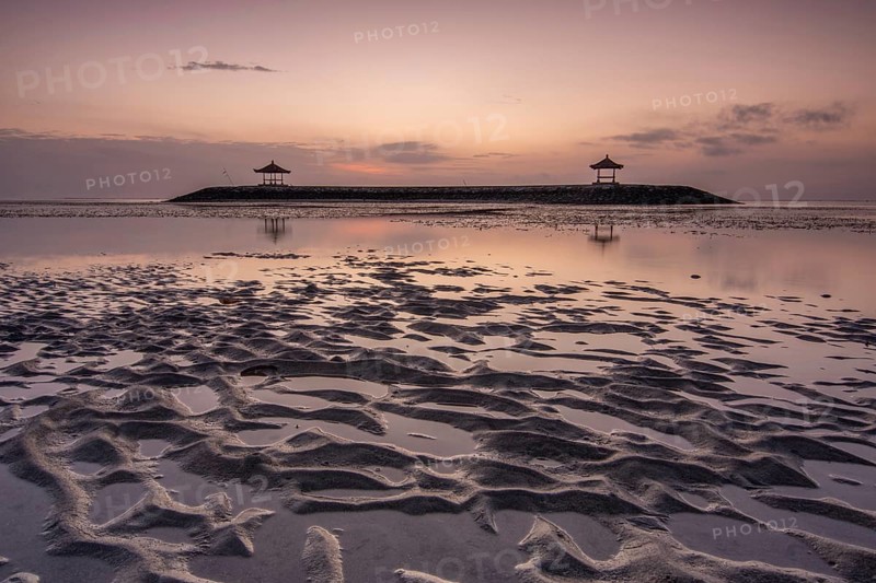Fantastic sunrise on the beach with small temples. View of the sea as far as the horizon. Sanur, Bali, Indonesia, Asia