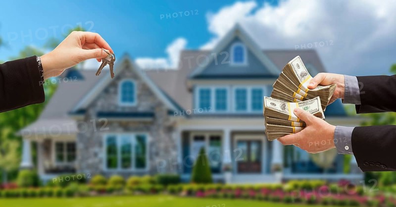 Real estate agent handing over house keys for stacks of money in front of new house