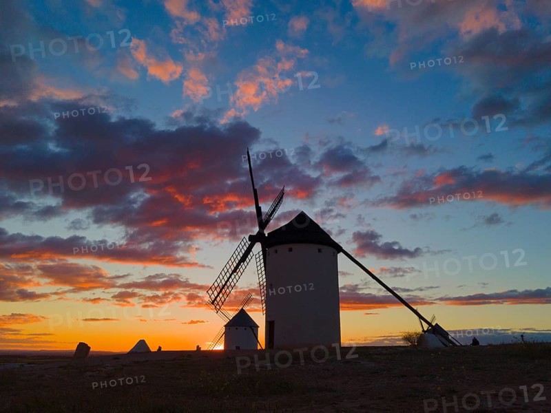 Windmills at dusk, silhouettes of buildings stand out against the colourful sky and scattered clouds, windmills, Campo de Criptana, Ciudad Real province, Castilla-La Mancha, Route of Don Quixote, Spain, Europe