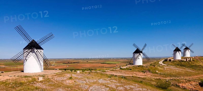 Several white windmills spread across a vast agricultural area under a clear blue sky, aerial view, Alcazar de San Juan, Ciudad Real, Castilla-La Mancha, Route of Don Quixote, Spain, Europe