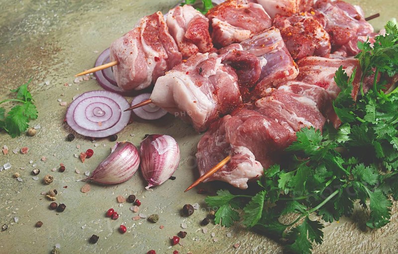 Raw pork meat, on wooden skewers, pickled kebab, with spices and herbs, on the table, top view, no people