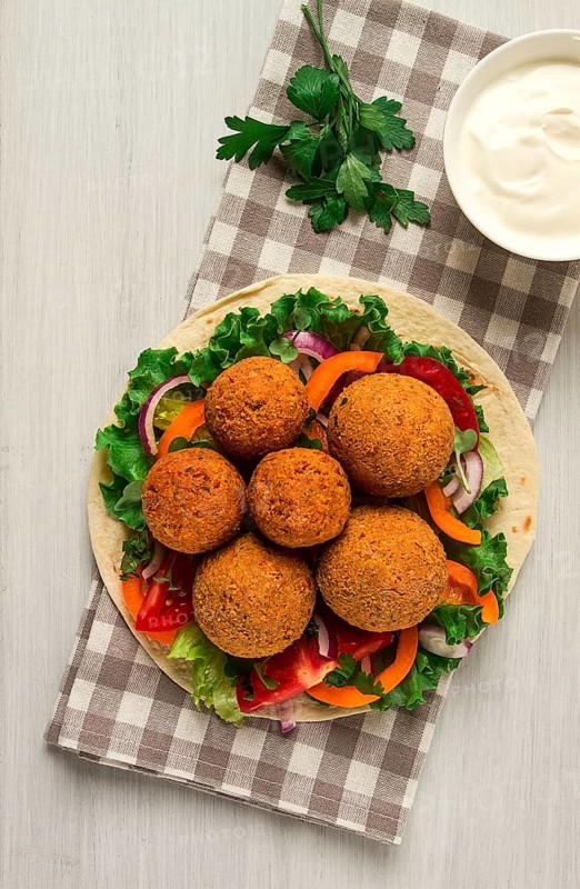 Tortillas, wrapped falafel balls, with fresh vegetables, vegetarian healthy food, on a wooden white background, no people, selective focus
