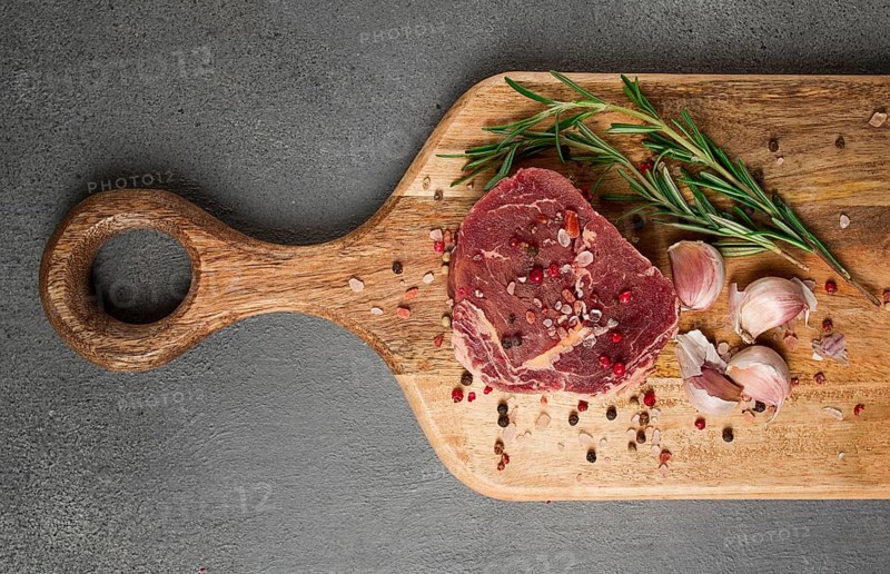Fresh, raw rib eye steak, on a chopping board, top view, no people