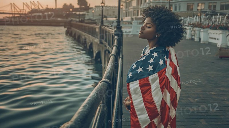 Pensive woman draped in an American flag, standing by the waterfront at dusk, AI generated