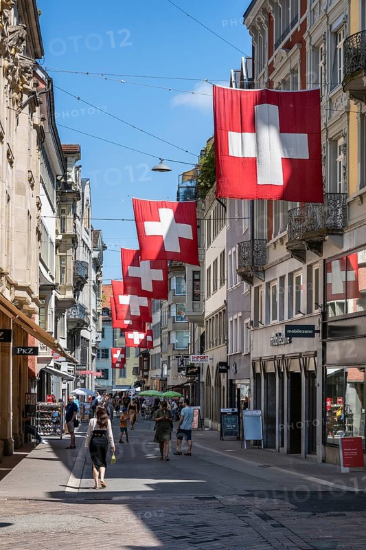 The Multergasse, pedestrian zone, shopping alleyway, decorated with Swiss national flags in the monastery quarter, historic old town of Sankt Gallen, Canton of St. Gallen, Switzerland, Europe