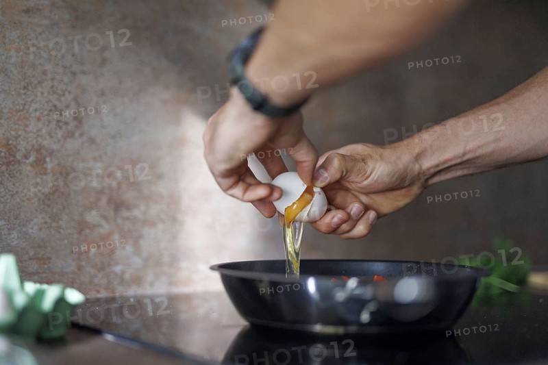 Cooking topic. A man cracks a raw egg into a pan. Berlin, 01.08.2024