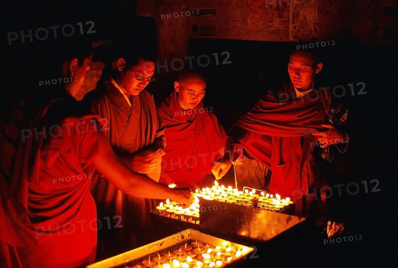 Tibetan buddhist monks and nun are lighting candles at night during the Buddha purnima festival (Swayambhu, Nepal), The festival is commemorating the life of the Buddha