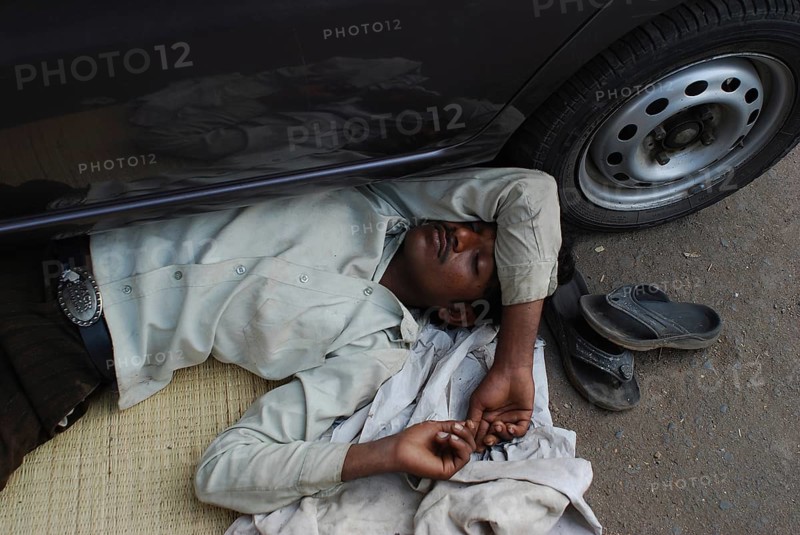 Man sleeping under a car (Mumbaï, India) . He belongs to the dalit community