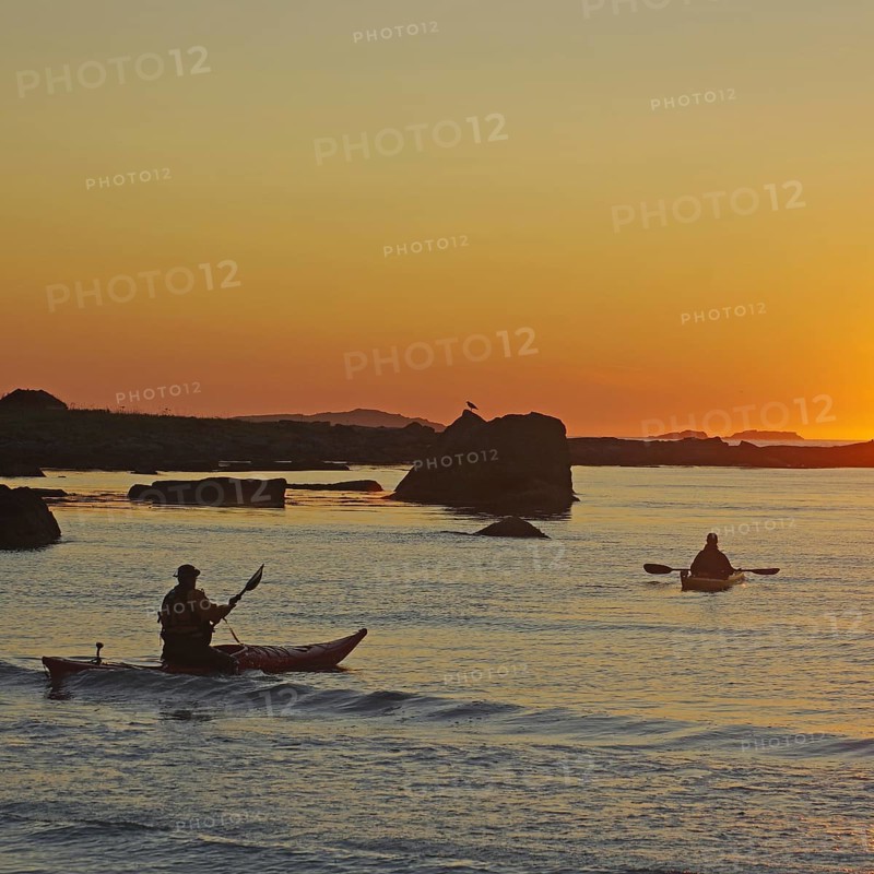 Two people kayaking on a calm water at sunset, Ramberg, Flakstad, Flakstadoya, Lofoten, Nordland, Norway, Europe