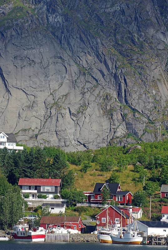 Idyllic fishing village with red house and fishing boats in front of an impressive rock face, Rorbuer, Hamnoy, Moskenes Lofoten, Nordland, Norway, Europe