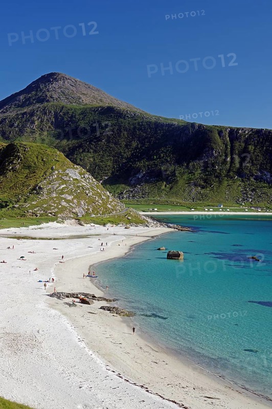 A picturesque beach with blue sea and people, surrounded by green mountains, Haukland, Leknes, Lofoten, Nordland, Norway, Europe