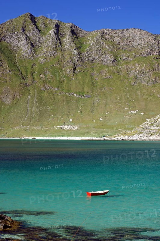 A red boat floats in a turquoise-coloured lake in front of a mountainous landscape, Haukland, Leknes, Lofoten, Nordland, Norway, Europe