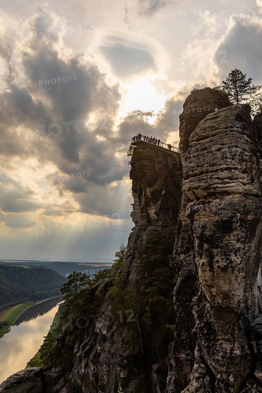 The Bastei is a rock formation with a viewing platform in Saxon Switzerland on the right bank of the River Elbe in the municipality of Lohmen between the spa town of Rathen and the town of Wehlen. It is one of the most visited tourist attractions in Saxon Switzerland. Dramatic sky over the Bastei. ourists on the new viewing platform, Saxon Switzerland, Rathen, Saxony, Germany, Europe