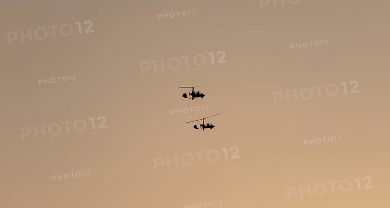 Two gyrocopters flying at sunrise, silhouettes against the morning sky, Mpumalanga, South Africa, Africa