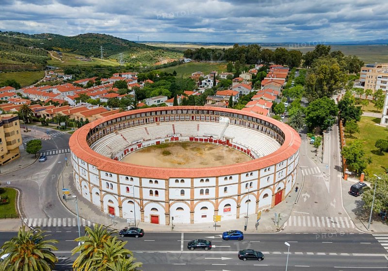 Aerial view of a historic bullring with red roofs in the middle of a city, surrounded by green trees and streets under a cloudy sky, aerial view, bullring, Caceres, Caceres, Caçris, Extremadura, Spain, Europe