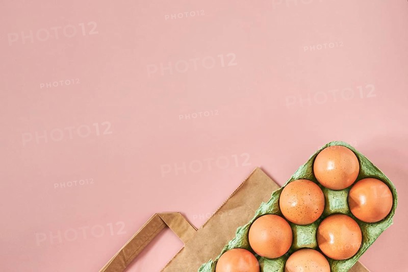 Kraft bag with chicken eggs in tray on beige background, shopping concept, space for text