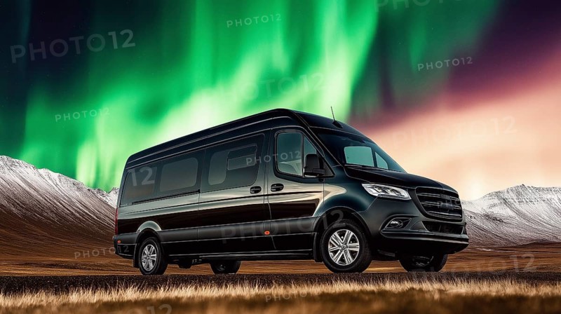 A van parked in a wilderness setting with the northern lights illuminating the sky above a mountain range, AI generated