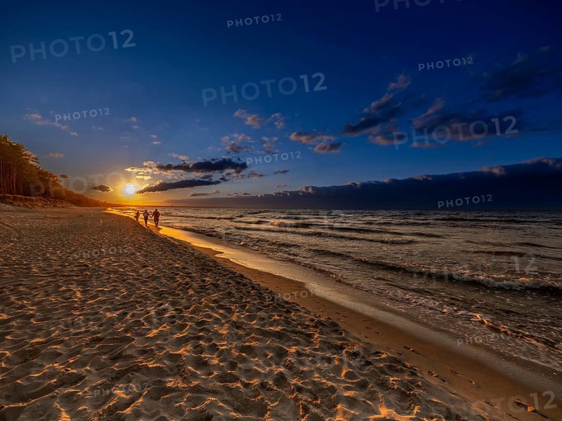A couple holding hands at sunset on the sandy beach on the island of Usedom on the Baltic Sea, Zempin, Mecklenburg-Vorpommern, Germany, Europe