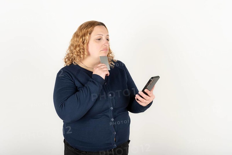 Woman shopping online holding her phone and credit card