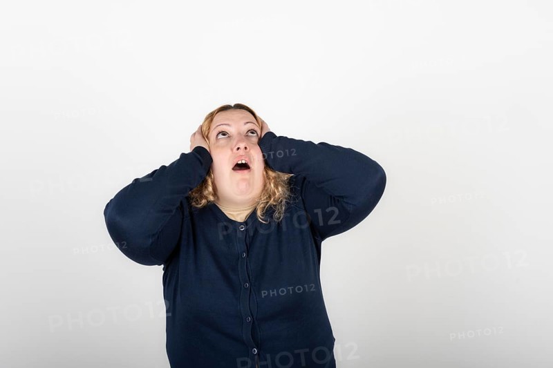 Plus size woman with a tired expression grabs her head and looks up