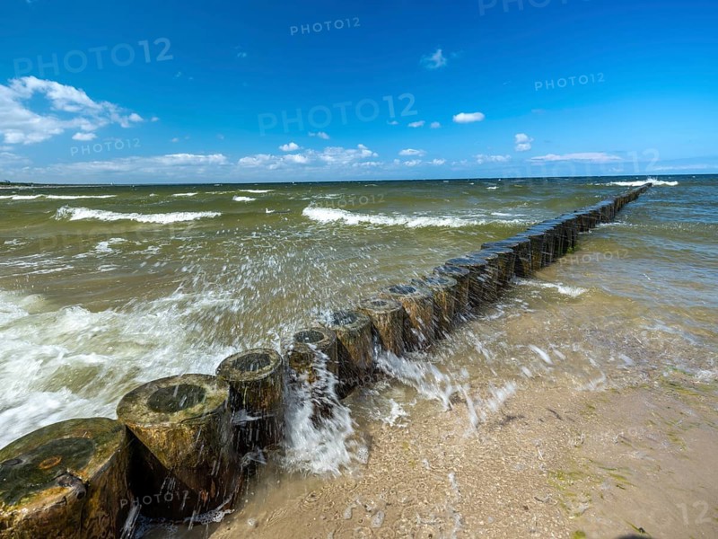 Spray splashes on a wooden groyne on a sandy beach on the Baltic Sea on the island of Usedom, clouds in the blue sky, Zempin, Mecklenburg-Western Pomerania, Germany, Europe
