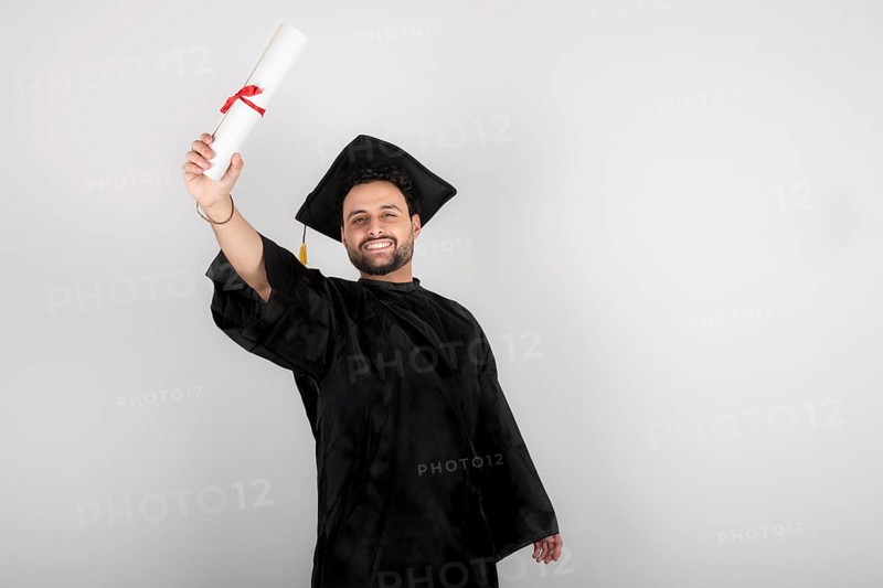 Recent graduate man, dressed in cap and gown, showing off his degree