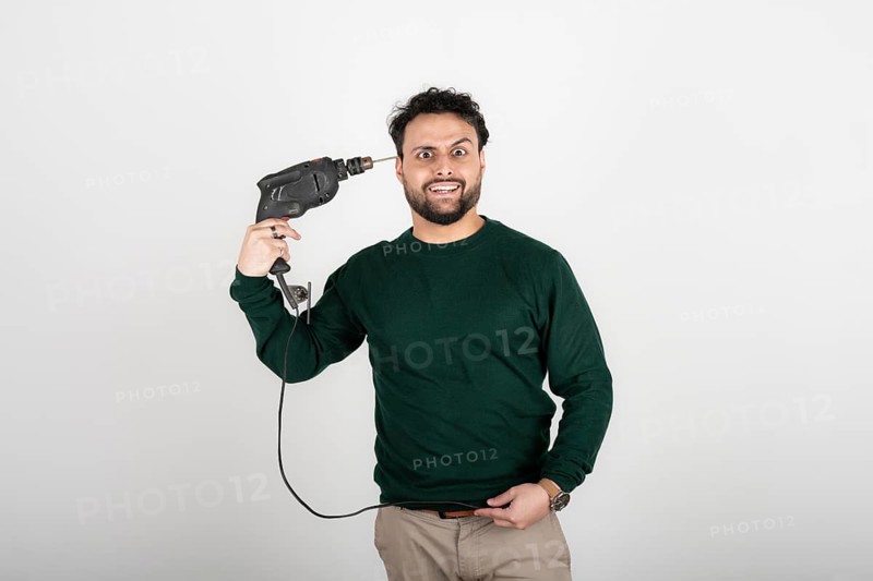 Stressed man putting drill against his head. Remodeling stress concept. Burnout concept