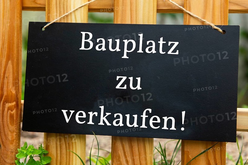 Sign with the inscription BAUPLATZ ZU VERKAUFEN on a wooden fence (symbolic image)