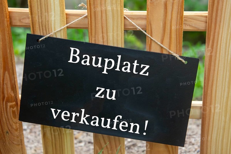 Sign with the inscription BAUPLATZ ZU VERKAUFEN on a wooden fence (symbolic image)